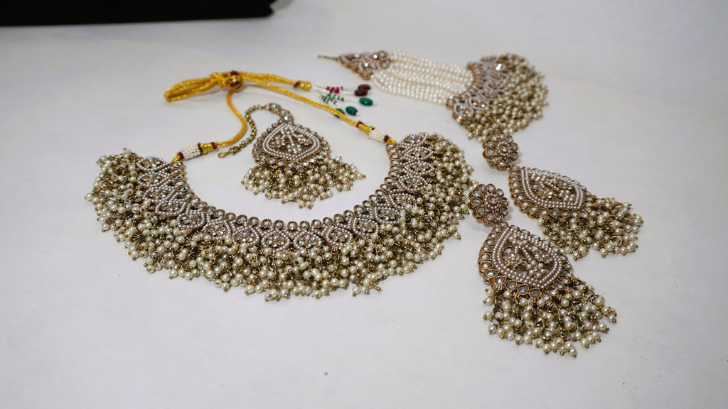 Regal Antique Gold-Toned Jewelry Set with Intricate Stonework, Maang Tikka, and Pearl-Fringed Passa