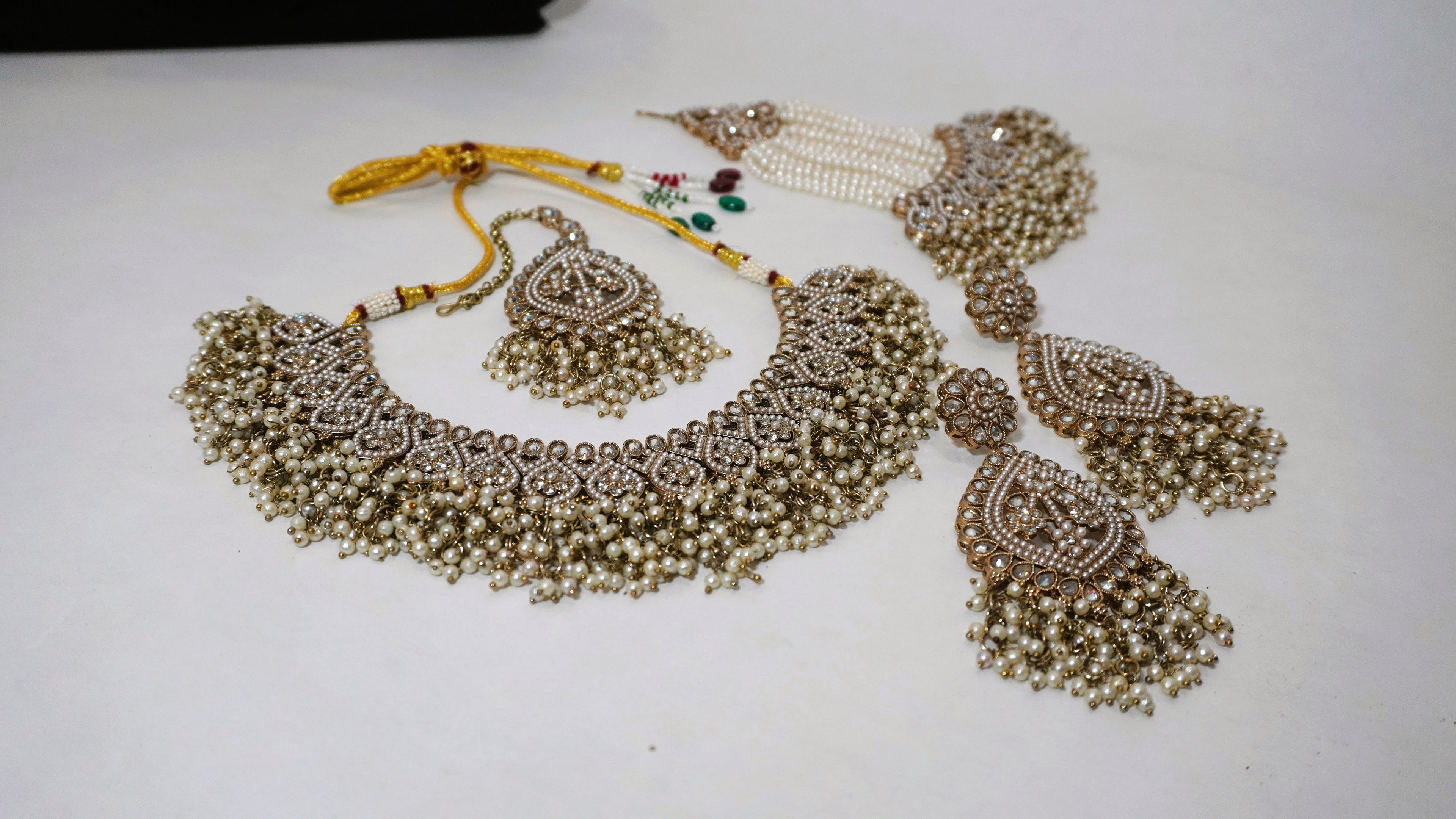 Regal Antique Gold-Toned Jewelry Set with Intricate Stonework, Maang Tikka, and Pearl-Fringed Passa